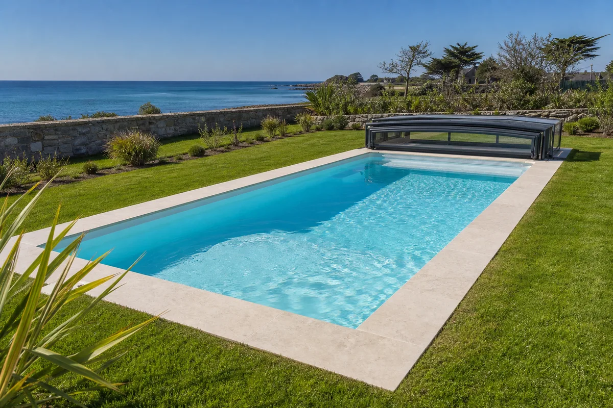Piscine coque achevée avec margelles claires et abri bas dans un jardin ensoleillé
